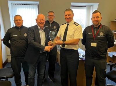 Chief Constable Russ Foster being presented with a crystalplaque by members of touring party